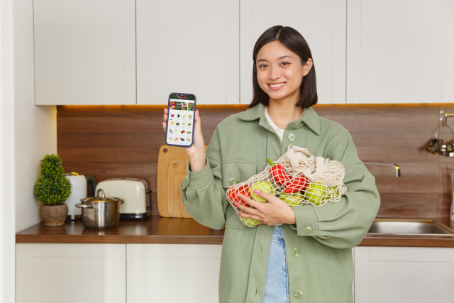 キッチンでスマホを掲げる女性