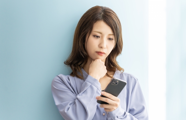 スマホをみて悩む女性