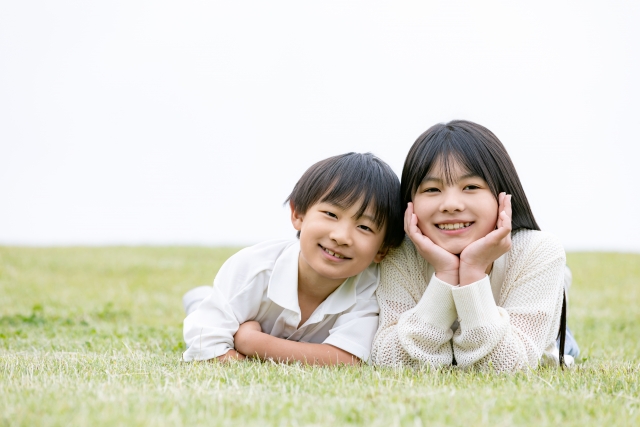 頬杖をついて微笑む小学生の姉と弟