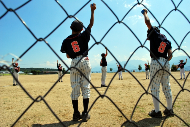 手をあげる少年野球の子ども