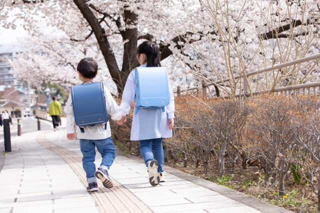 ランドセルを担いで手をつないであるく姉と弟